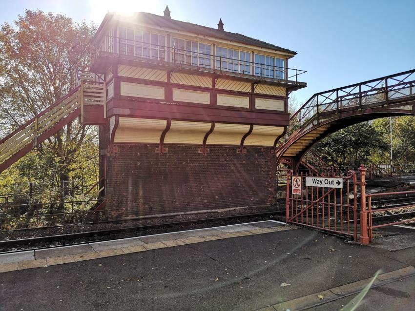 Signal box painted in heritage colours with the sun beaming across the roof with blue sky 