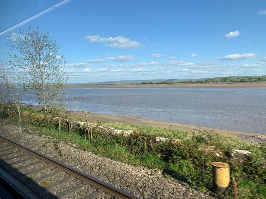 view from the train of estuary water and blue sky with fluffy white clouds