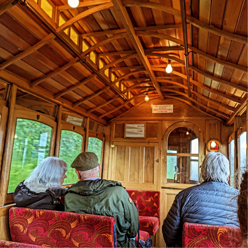 Wood roof with  lights and people sat in train carriage