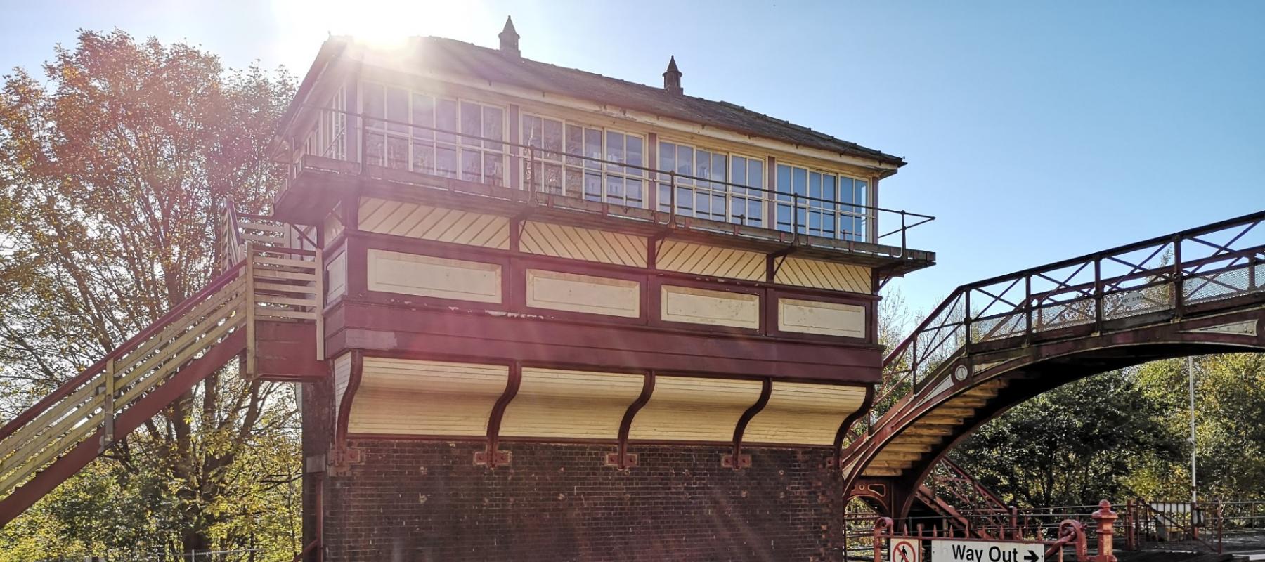 Signal box painted in heritage colours with the sun beaming across the roof with blue sky 