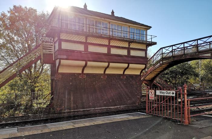 Signal box painted in heritage colours with the sun beaming across the roof with blue sky 