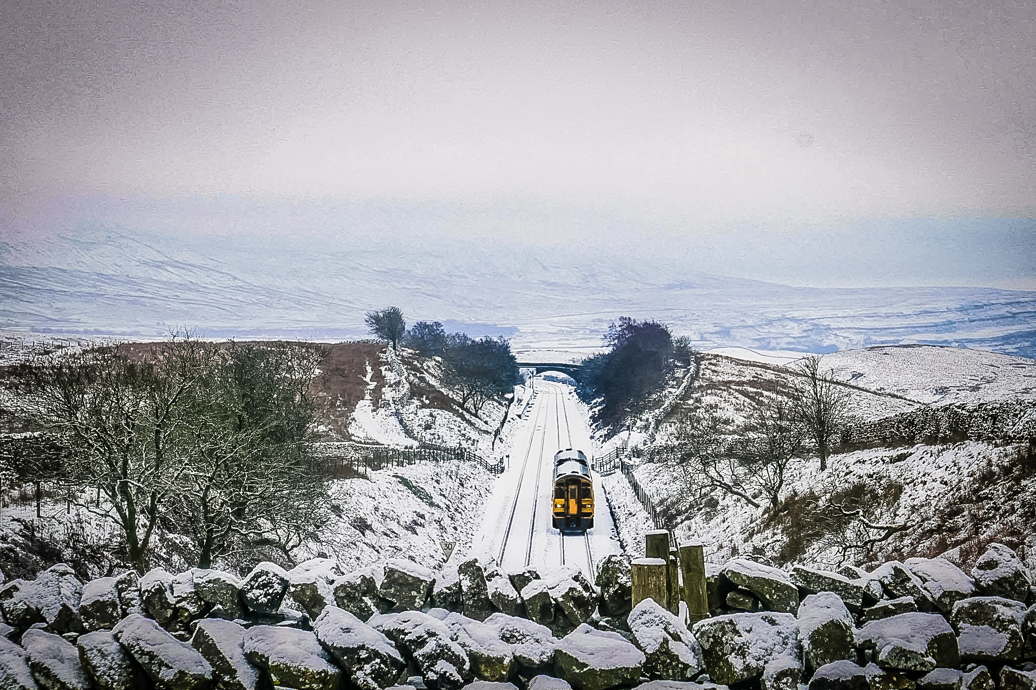 View from above of Settle to Carlisle line covered in snow with the surrounding landscape dusted with snow