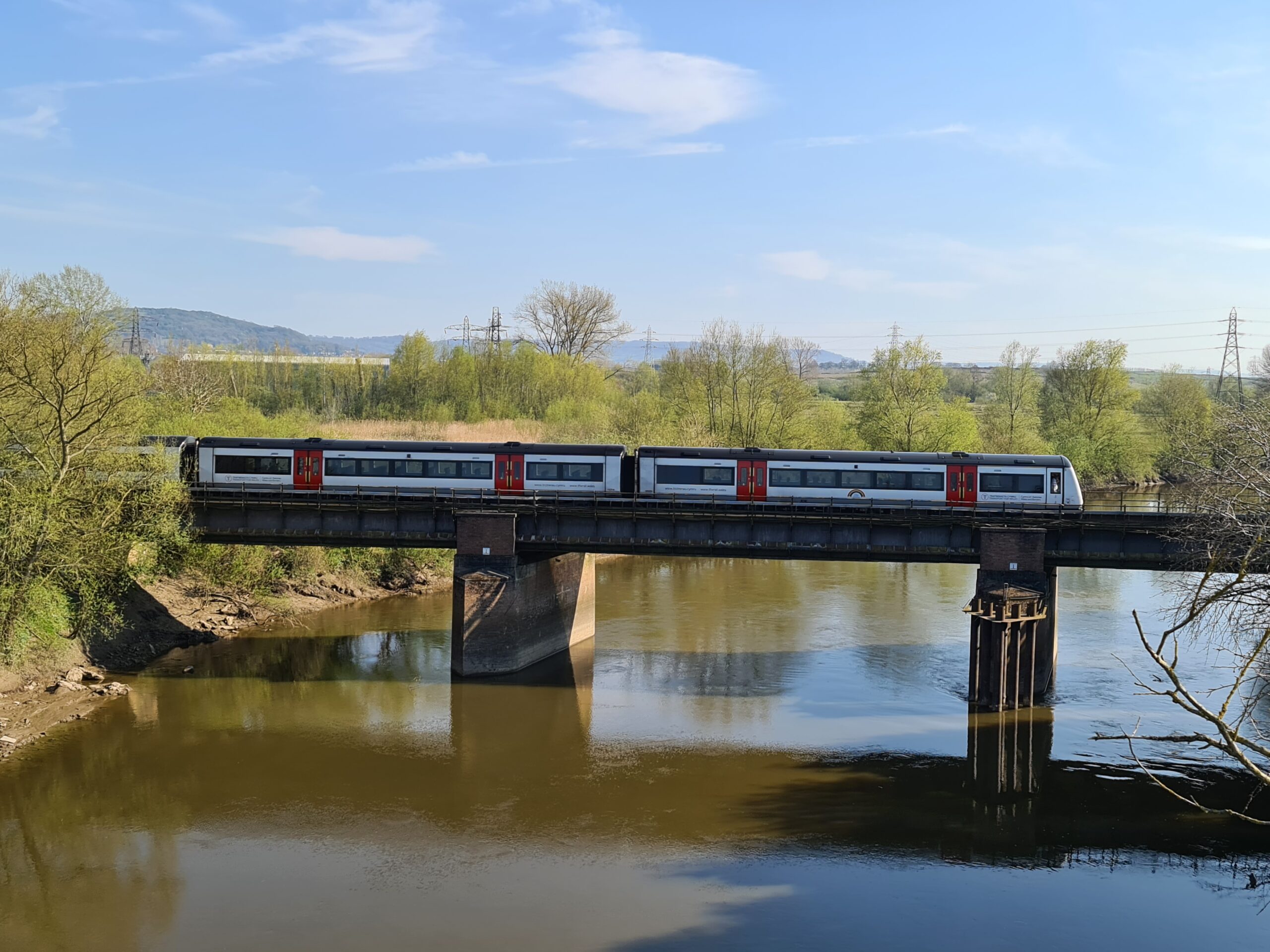 Seven Shores Line, train crossing a river in the sunshine.