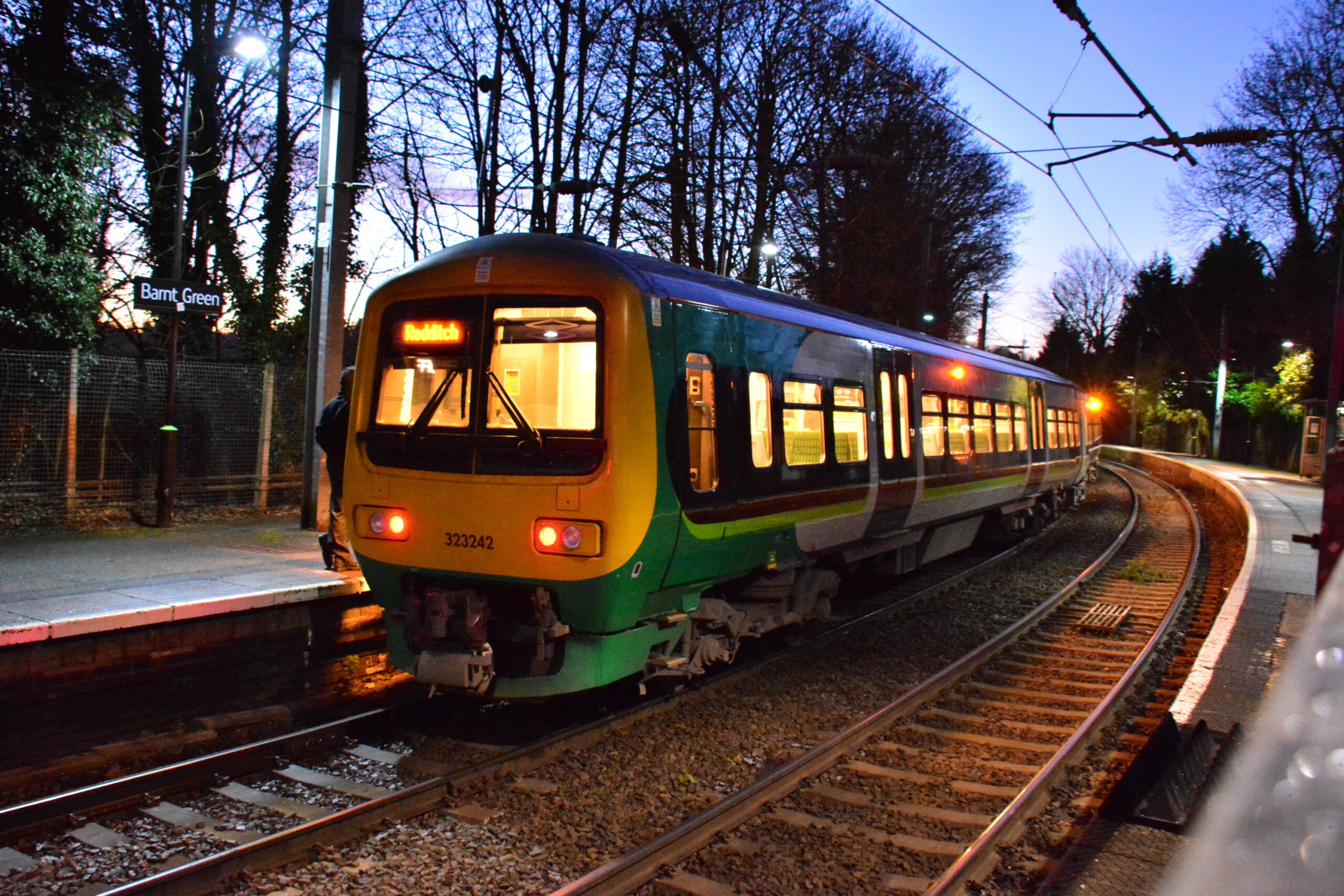 Barnt Green station in the evening glow with train at station