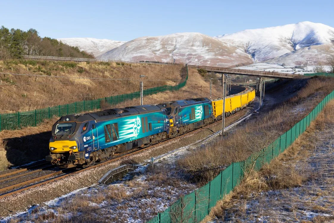 West Coast Main Line - train travelling in foreground with snowy winter fells in the background - Scenic Rail in Winter