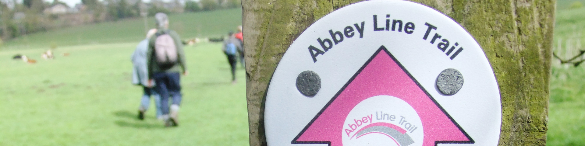 Abbey Line Trail marker with walkers in background