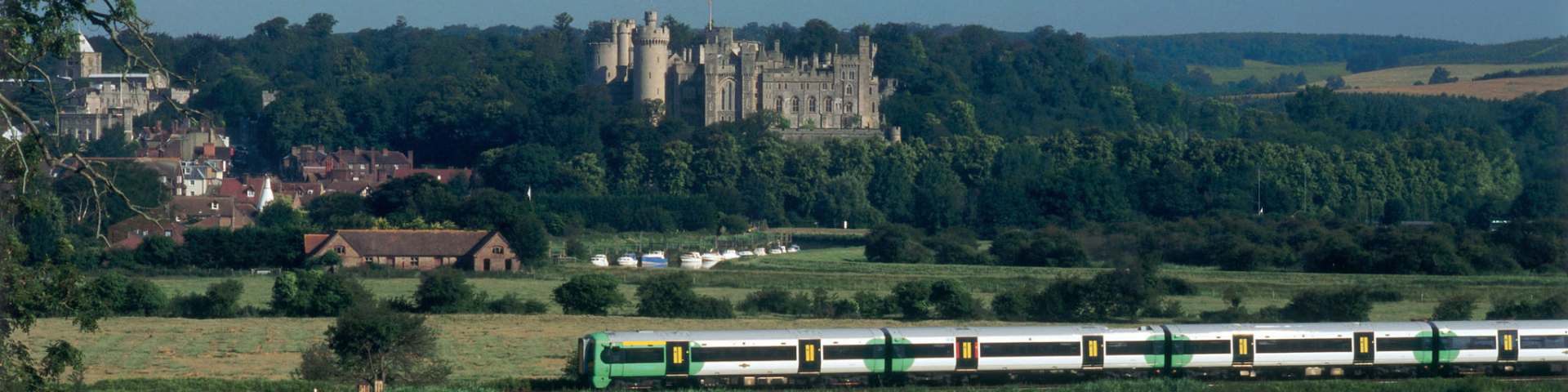 Arun Valley train pasing through countryside with Arundel Castle and forest in the background