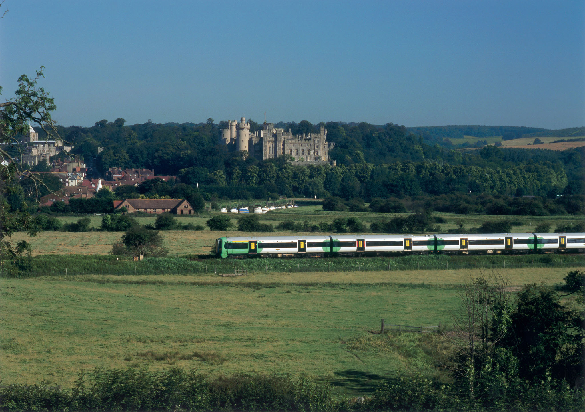 Arun Valley train pasing through countryside with Arundel Castle and forest in the background