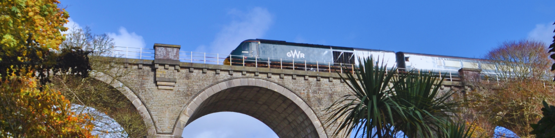 GWR train passing over viaduct with blue sky in background along the Atlantic Coast Line to Newquay by train