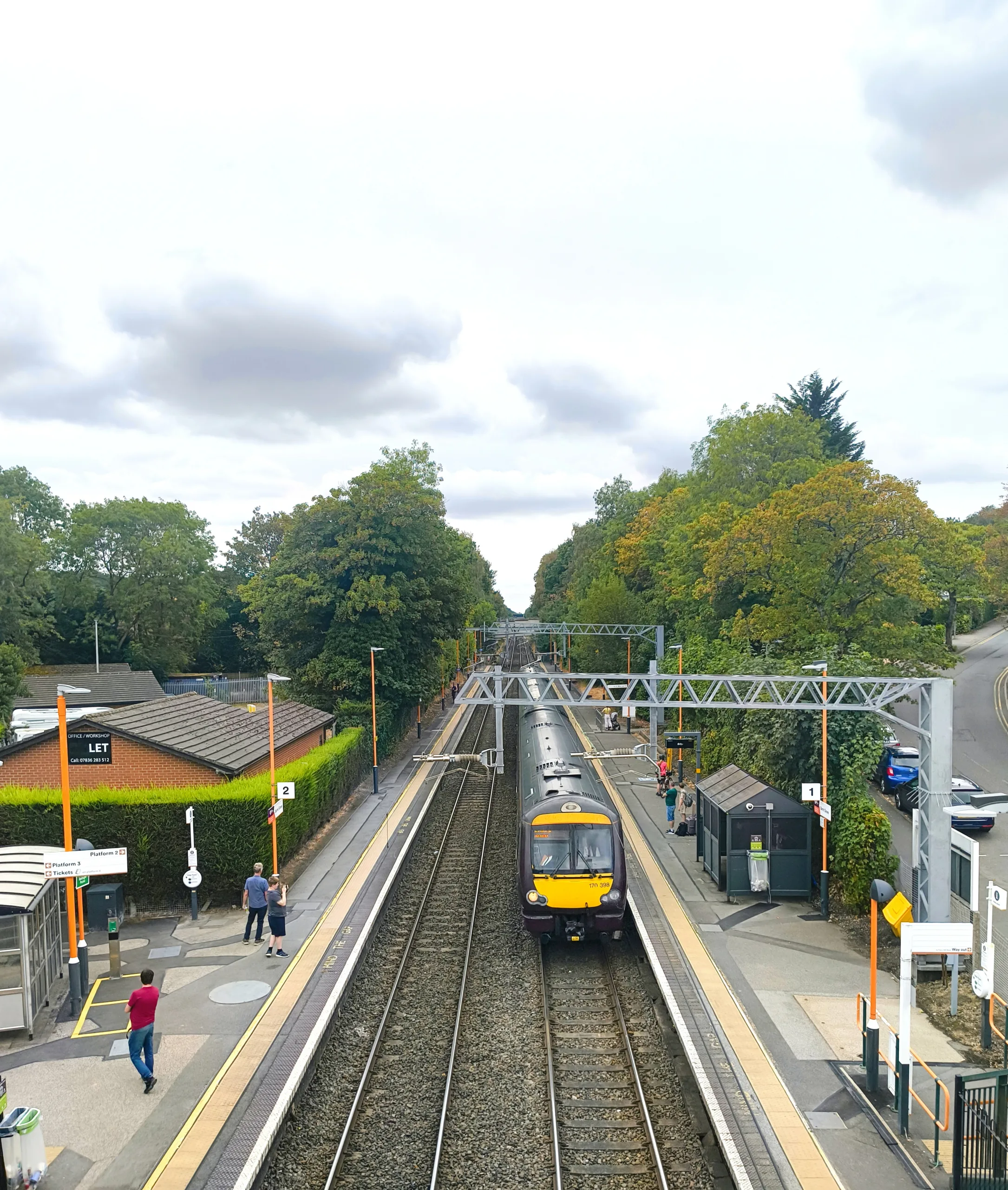 View of Barnt Green Station looking down from the passenger bridge, showing a train at the station. Along the Arrow Valley Line.