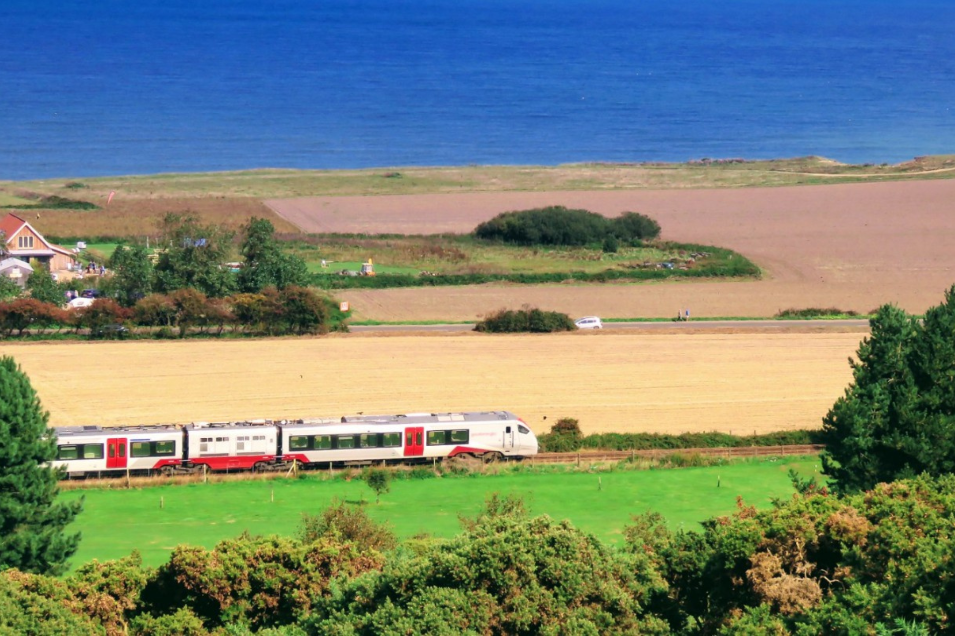 Bittern Line train travelling through fields with sea in distance