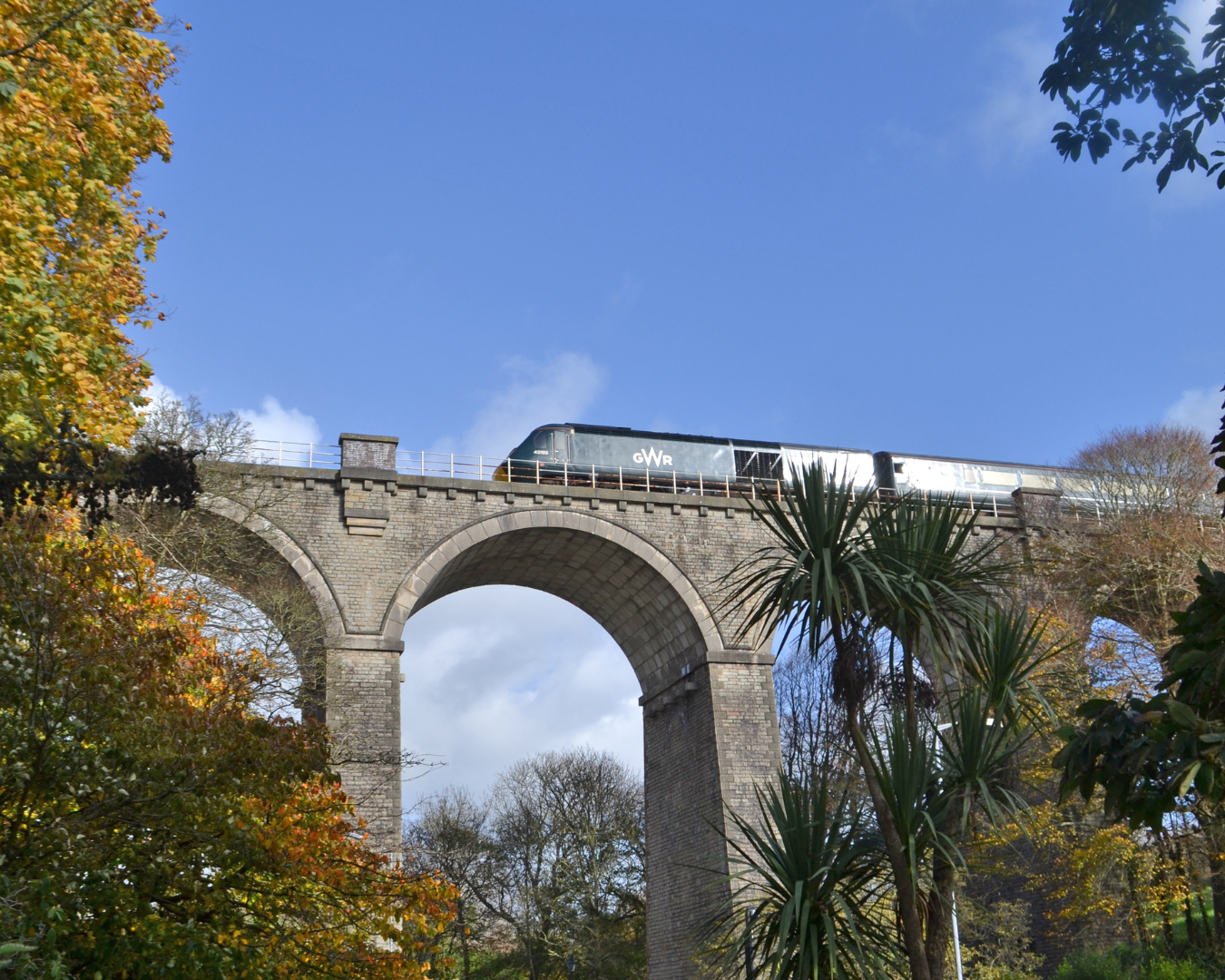 GWR train passing over viaduct with blue sky in background along the Atlantic Coast Line to Newquay by train