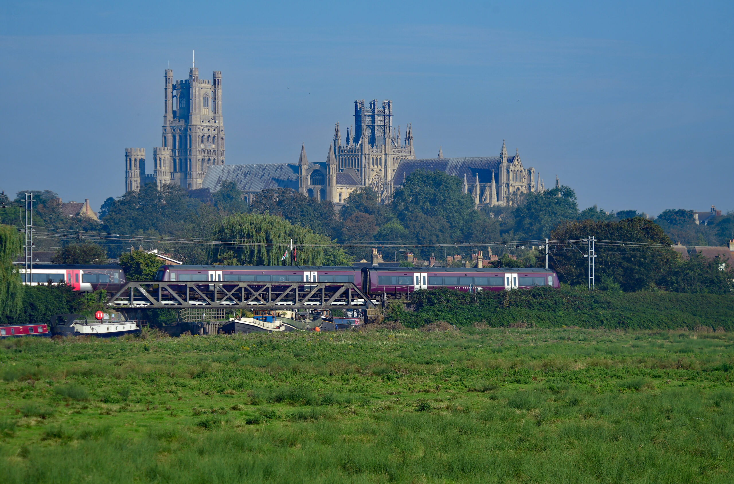 Ely Cathedral standing tall with EMR train travelling past below it