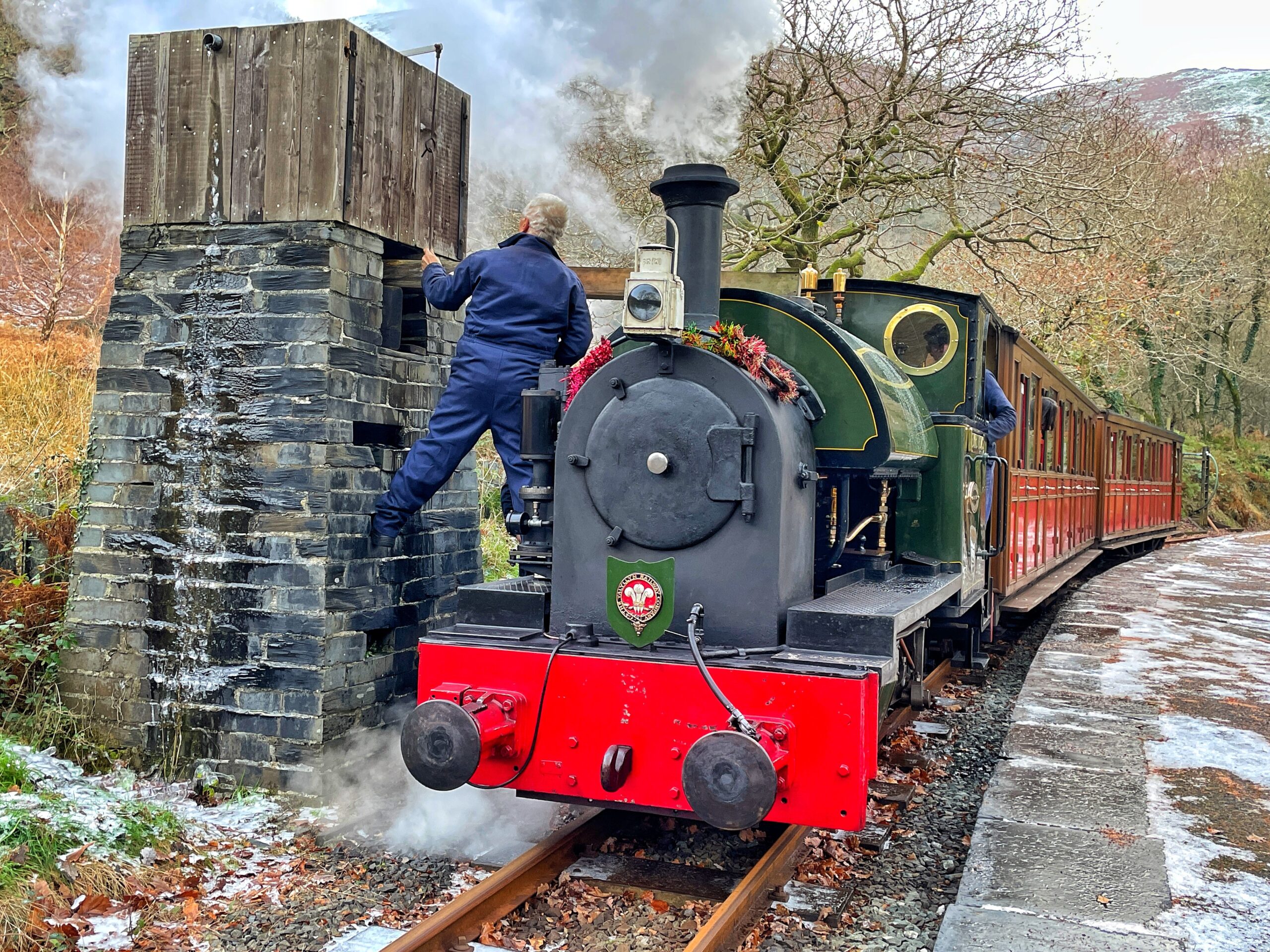 Steam train refilling with water along the Talynnyn Railway, Scenic Rail in winter