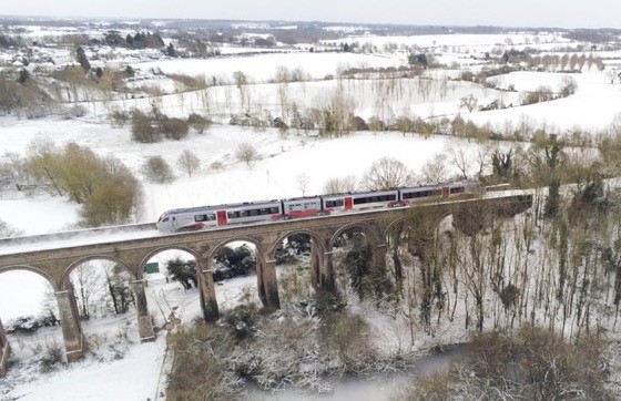 Traon travelling along a viaduct with surrounding countryside below covered in snow. Essex & South Suffolk