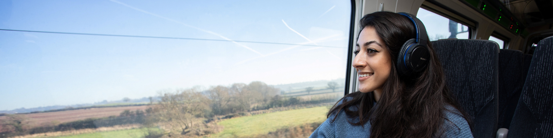 Person on train looking out the window at rolling countryside views