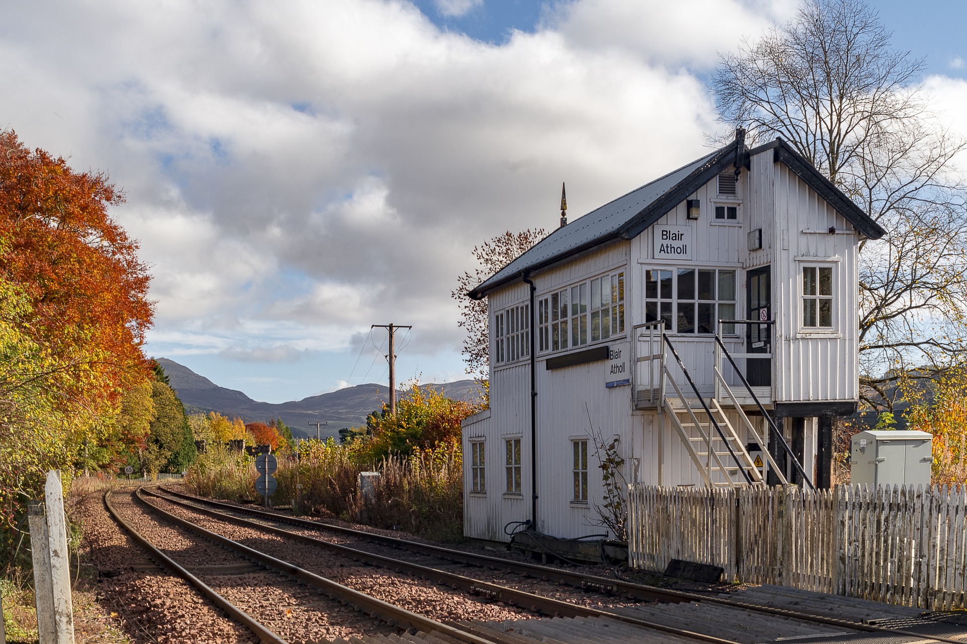 Signal box by the side of the train tracks with autumn coloured trees and Scottish Highlands in the background