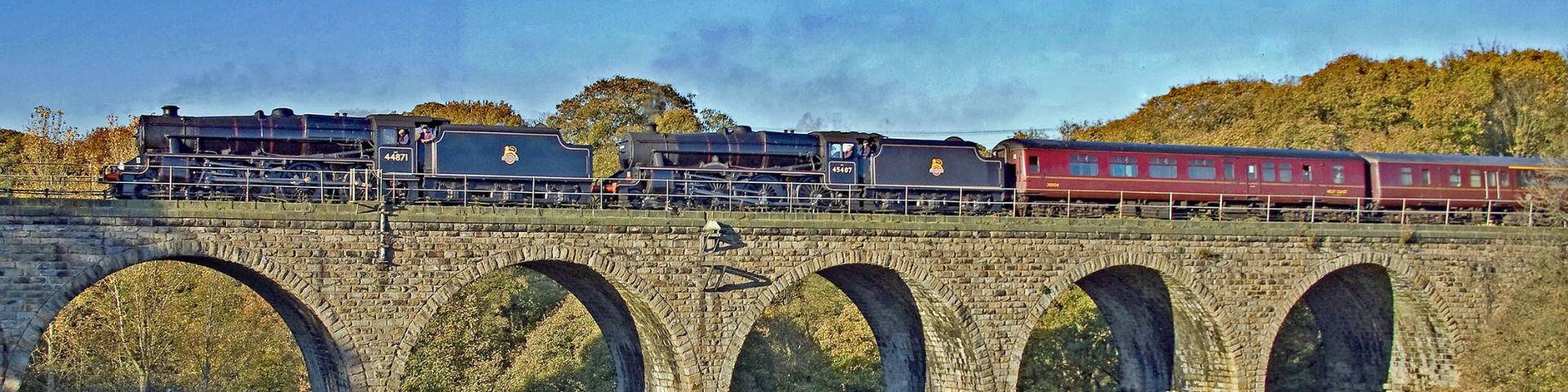 Steam train travelling along a viaduct on a sunny day | Penistone Line