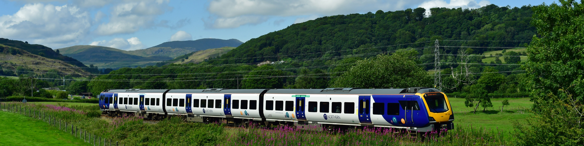 Train travelling by the side of Lae District fells along the Lakes Line