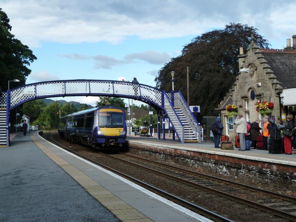 Train at Pitlochry station with footbridge painted in blue and white