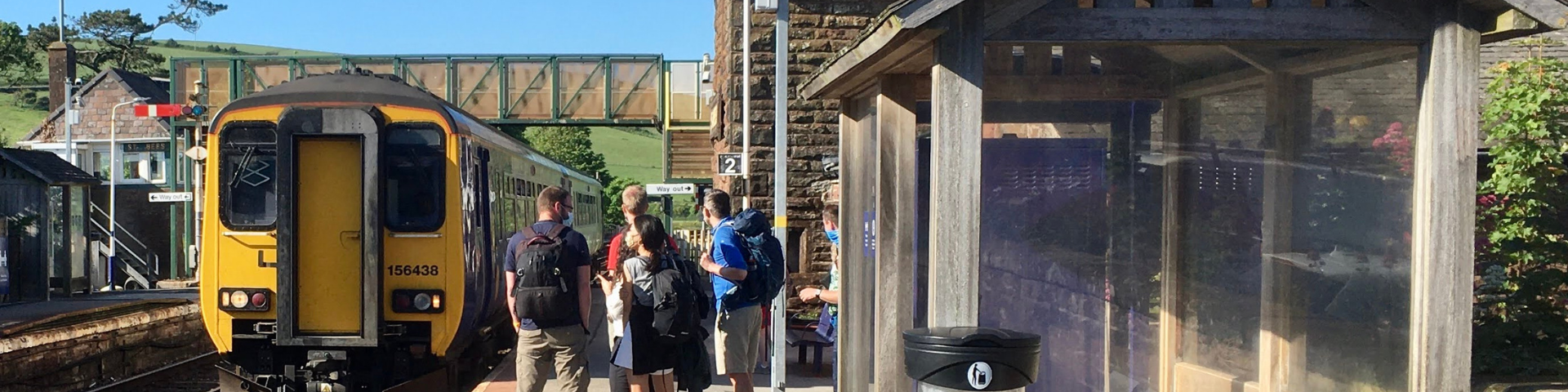 Group of people waiting for a train at a stone-built station | how railways boost local economies