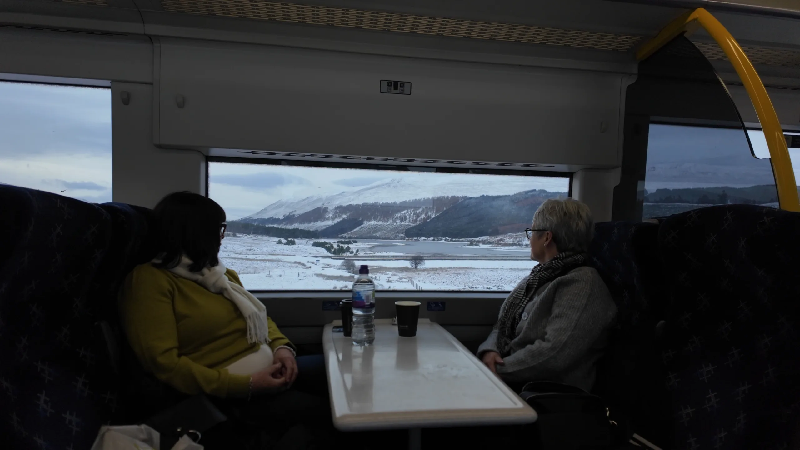 People on train looking at the snowy scenery from the window | Glasgow to Inverness | Scenic Rail in Winter