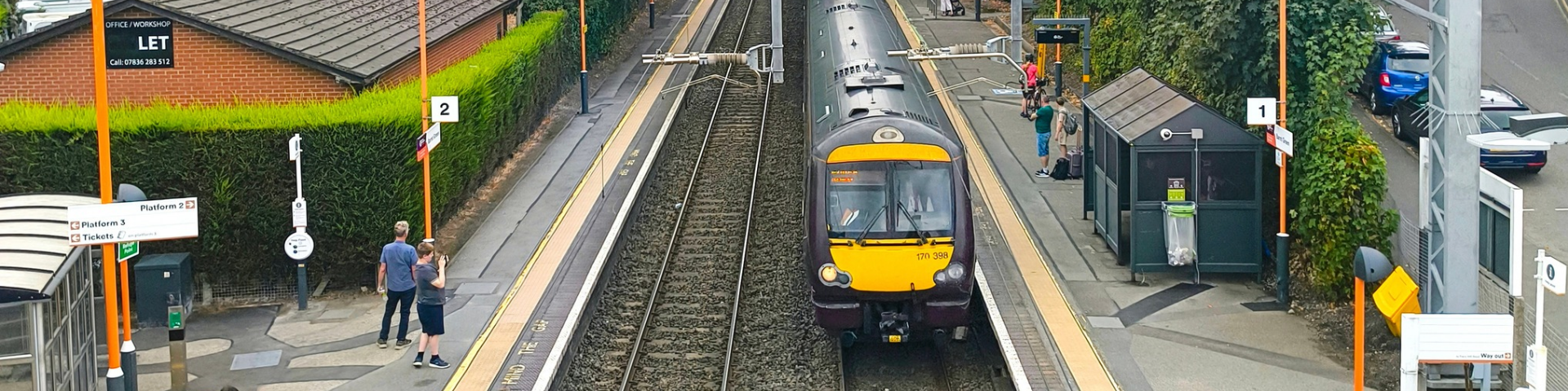 View of Barnt Green Station looking down from the passenger bridge, showing a train at the station. Along the Arrow Valley Line.