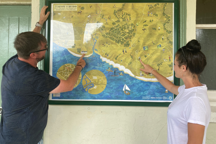 People looking and pointing at a Seaford and beyond map that is framed and on the wall