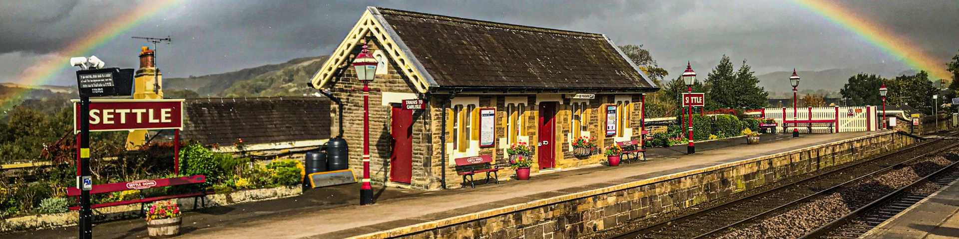 Stone built waiting room at Settle railway station with stormy clouds and rainbow