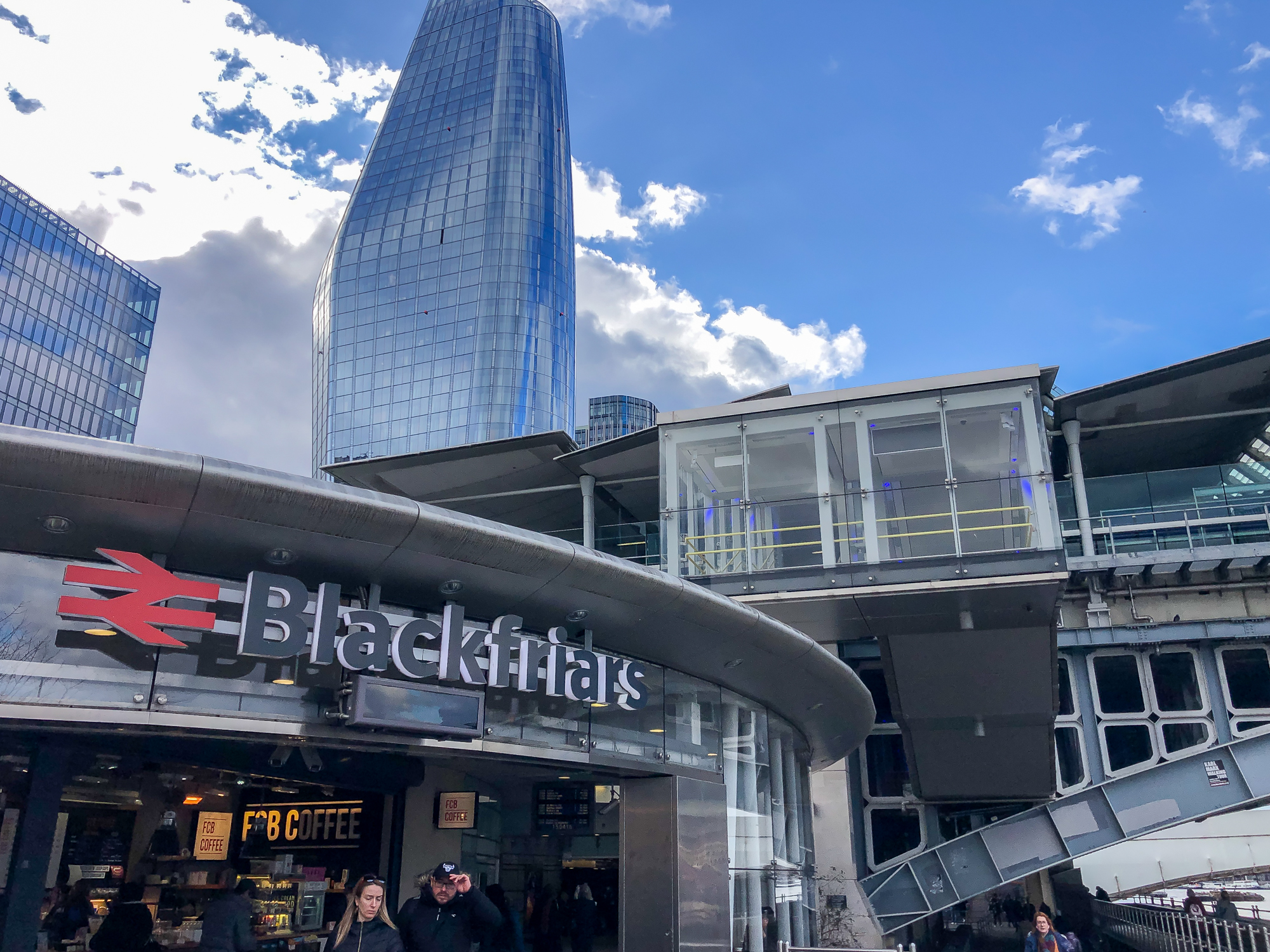 Blackfriars station entrance with tall building and blue sky towering over