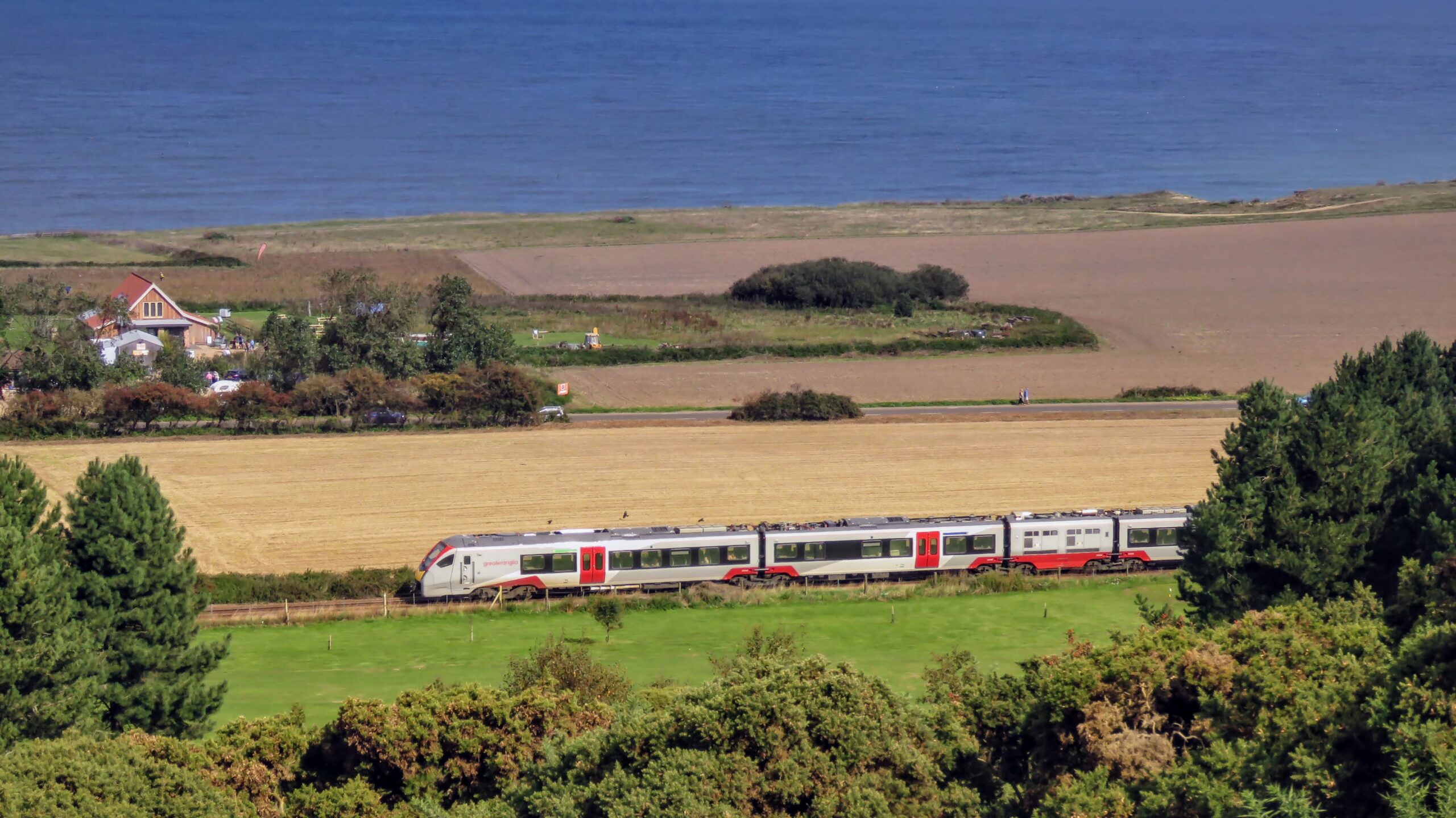 Greater Anglia train travelling along the Bittern Line with the sea in the background