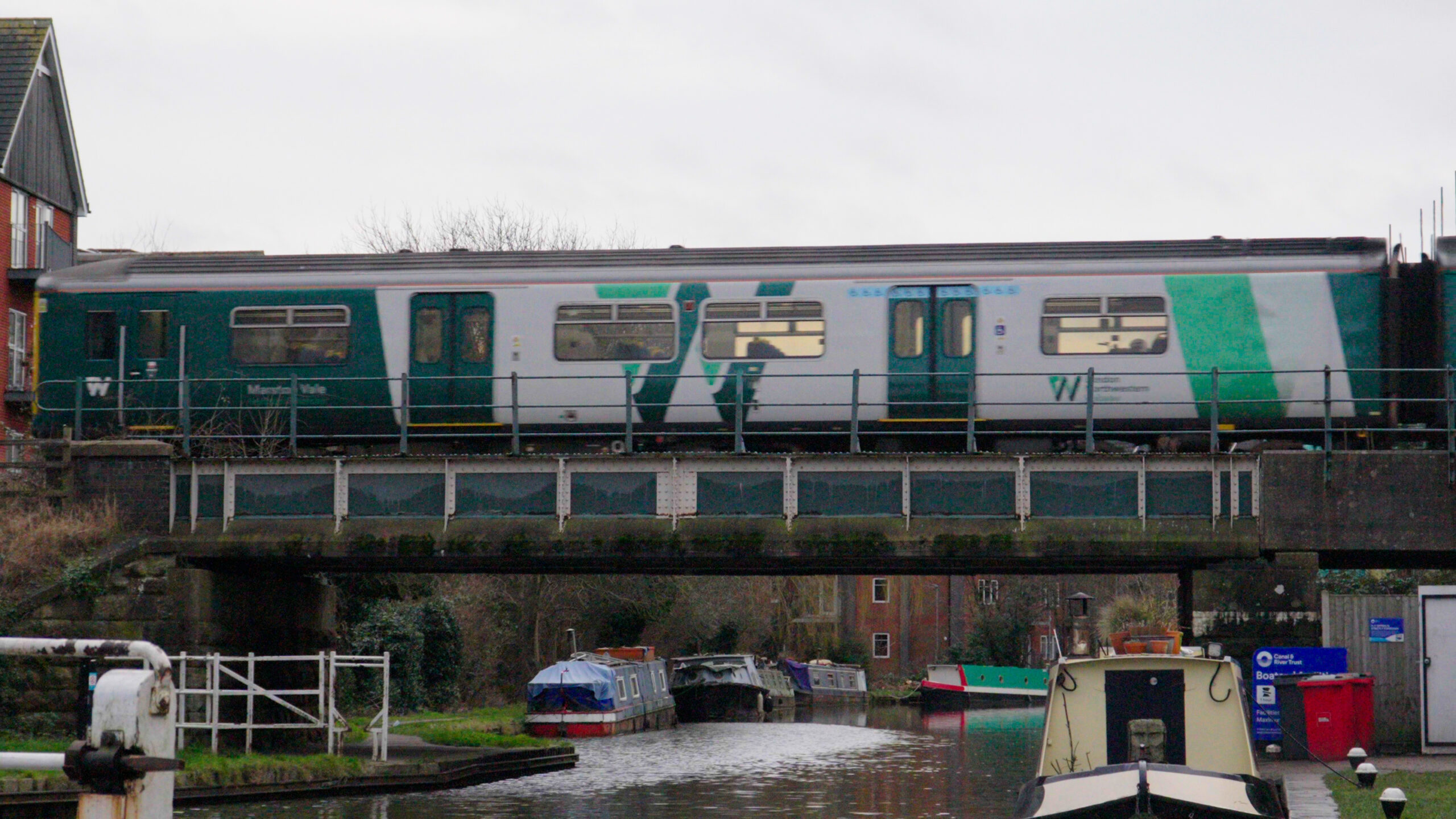 London Northwestern train travelling over canaln with riverboats underneath