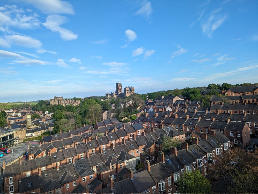 Houses with imposing Durham cathedral in the background against blue sky