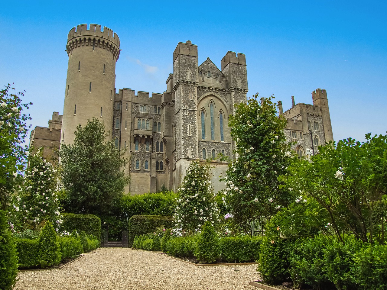 Arundel Castle with blue sky and surrounded by lush greenery in the gardens