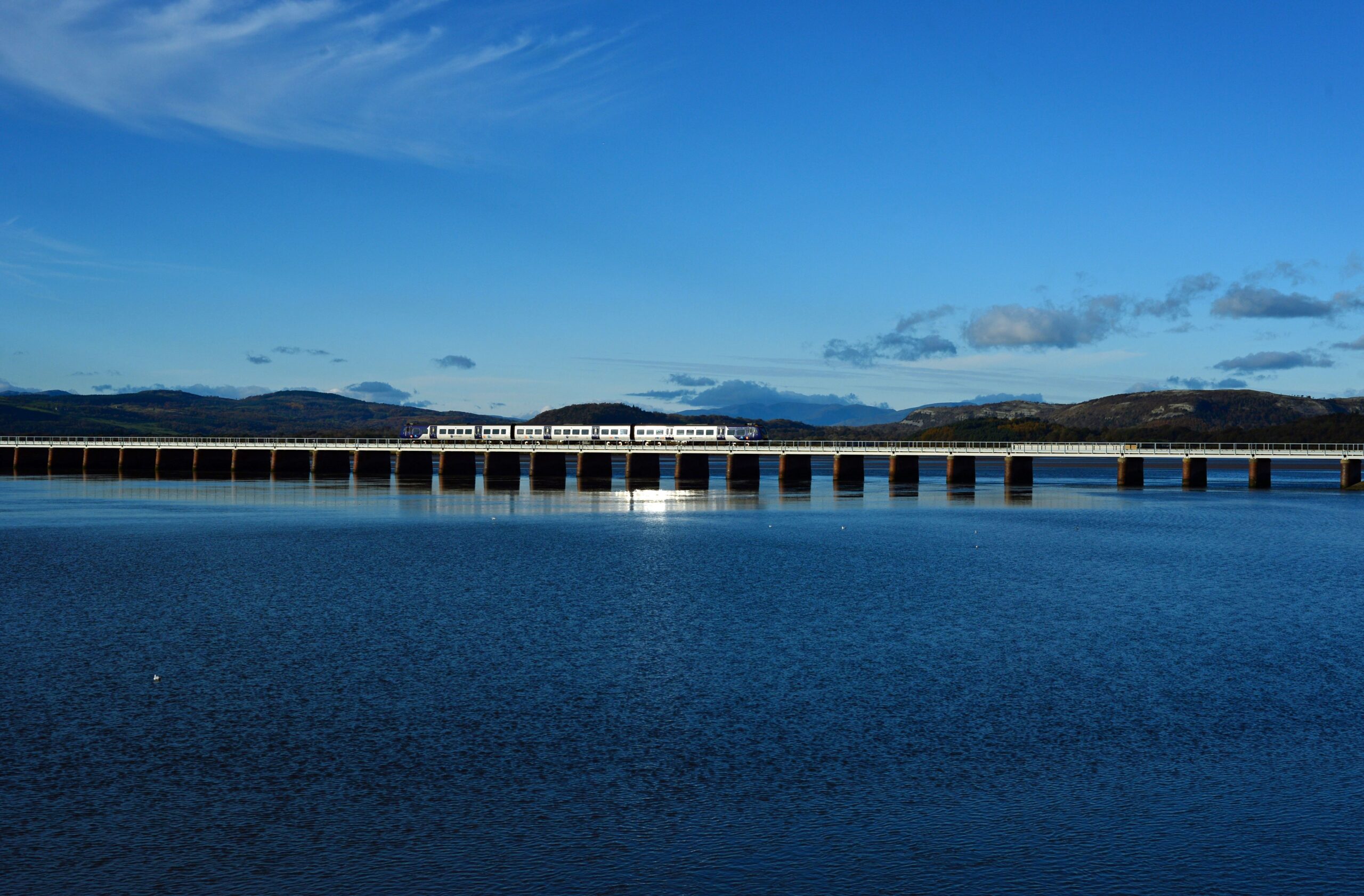 Train travelling across viaduct with Lake District mountain peaks in the distance