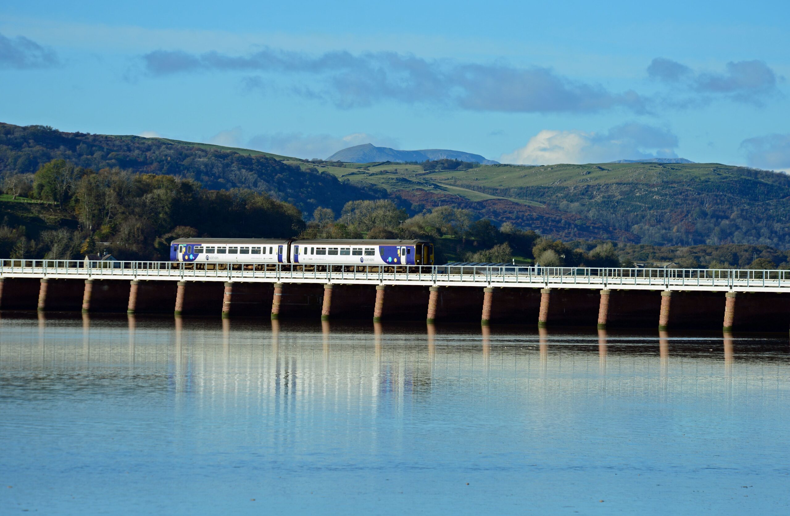 Train travelling over viaduct with Lake District fells in the background