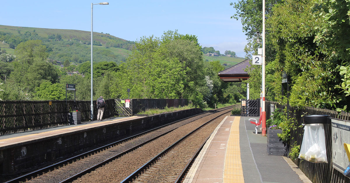 Mytholmroyd station with green countryside and hills in background