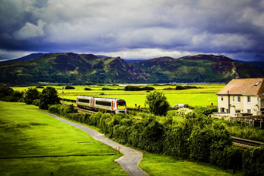 Train travelling through countryside with mountains in background