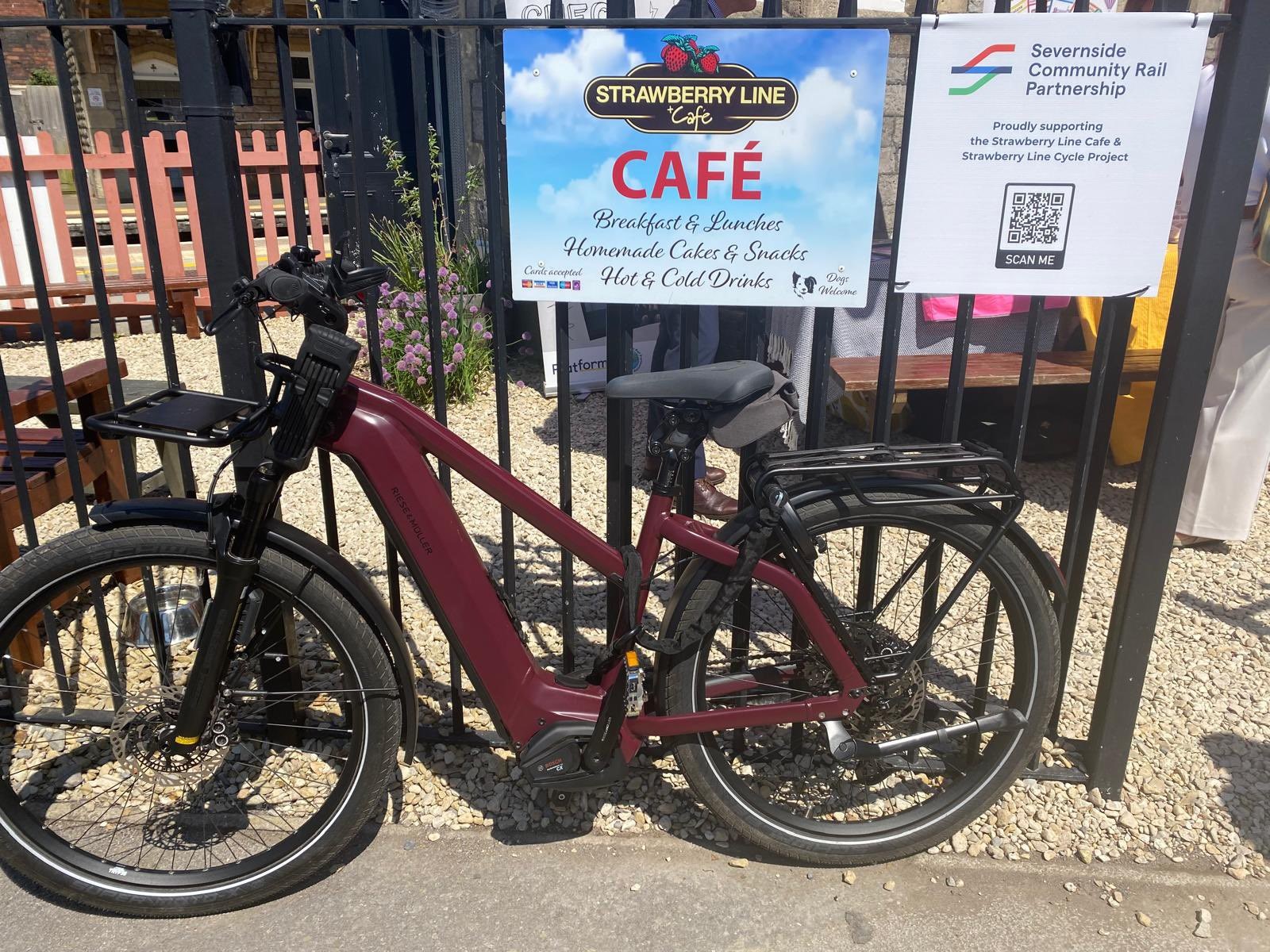 Bike against a fence with the sign saying 'Strawberry Line Cafe'