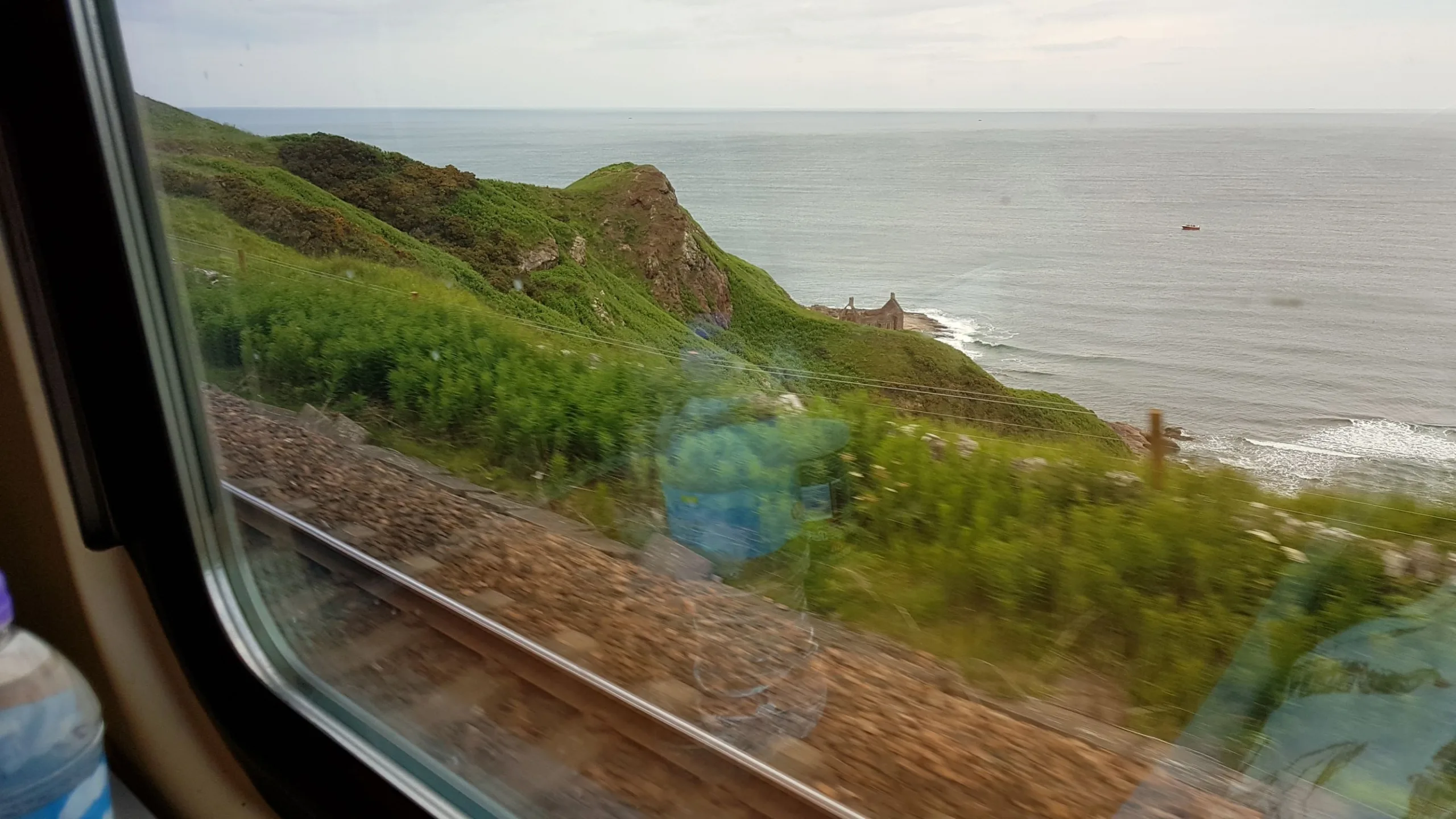 View of the sea with rugged cliffs, from the train - East Coast Main Line