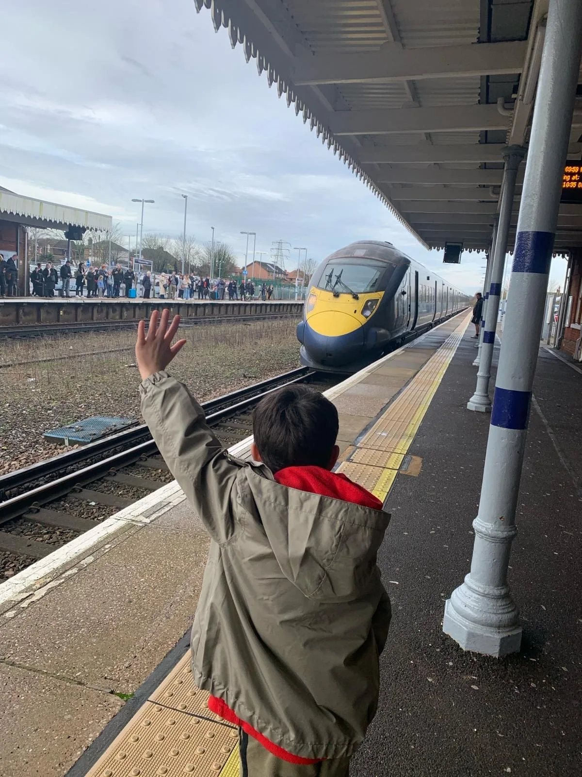 Child waving at train from platform | family adventures loved by locals