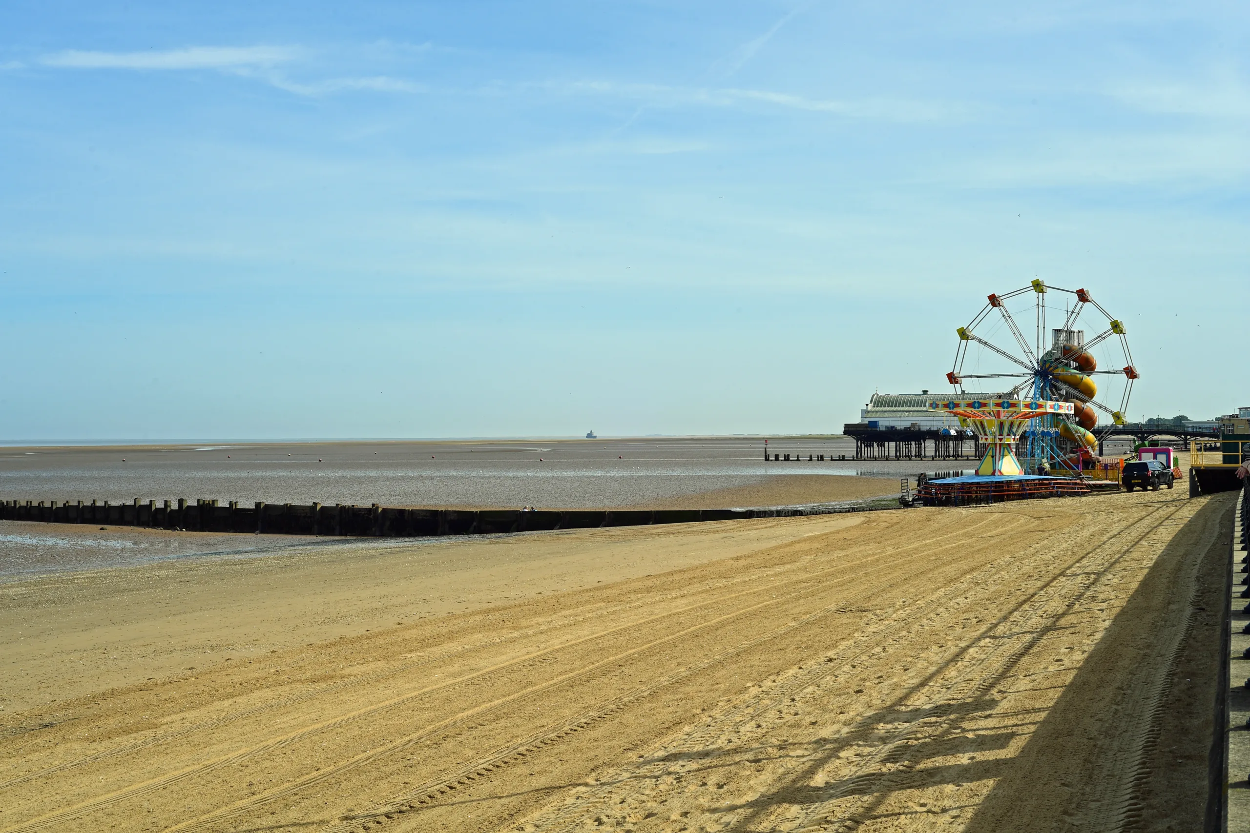 View of Cleethorpes sandy beach with the sea, ferris wheel and amusements in the background