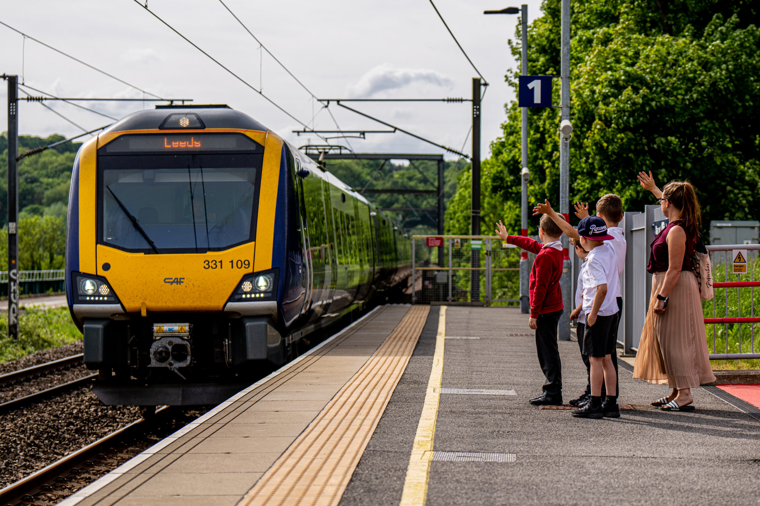Family waving at train as it approaches the station | Days Out by Rail