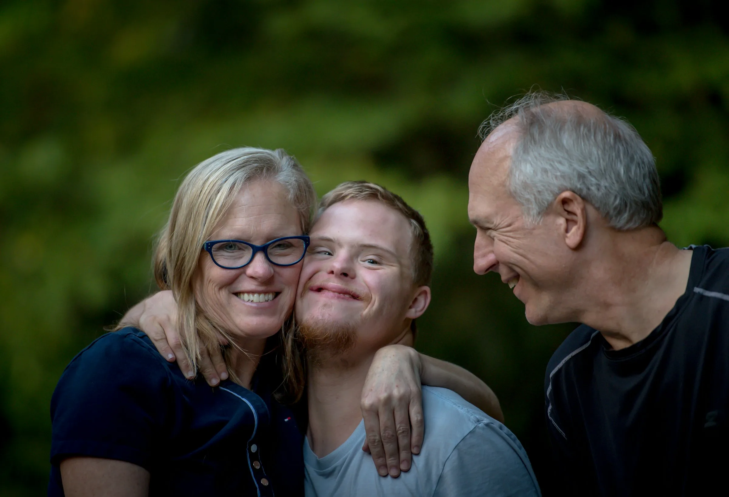 Three people smiling and hugging