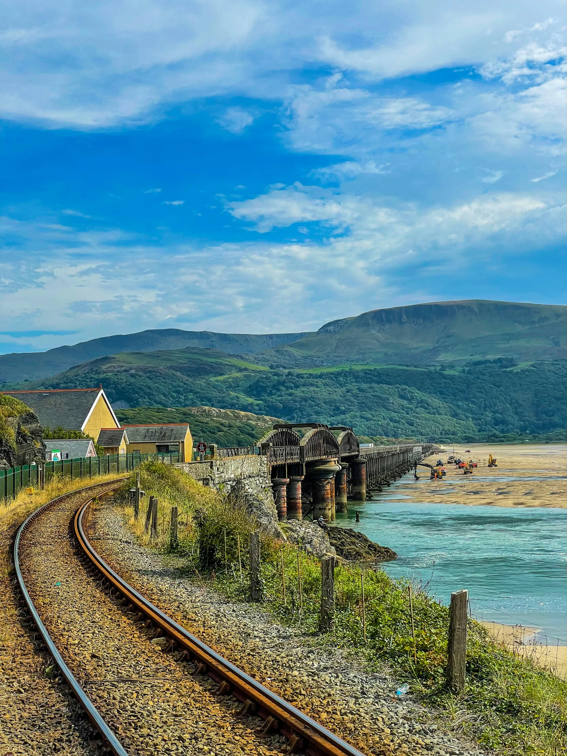 Train tracks leading to Barmouth Bridge with rolling hills and landscape in background | Wales walking and wheeling