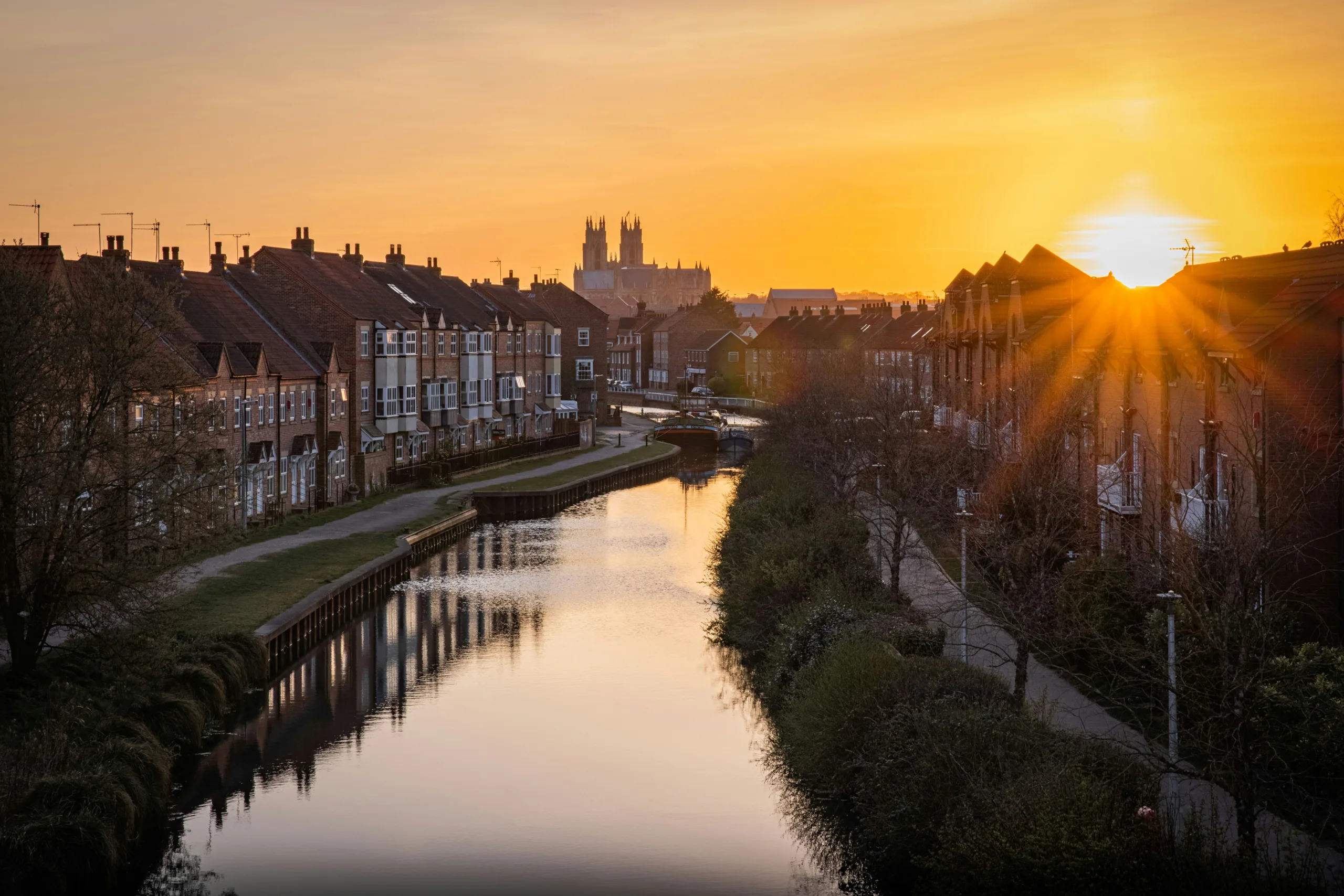 View of water with terraced houses either side and Beverley Minster in the background | stile-free routes