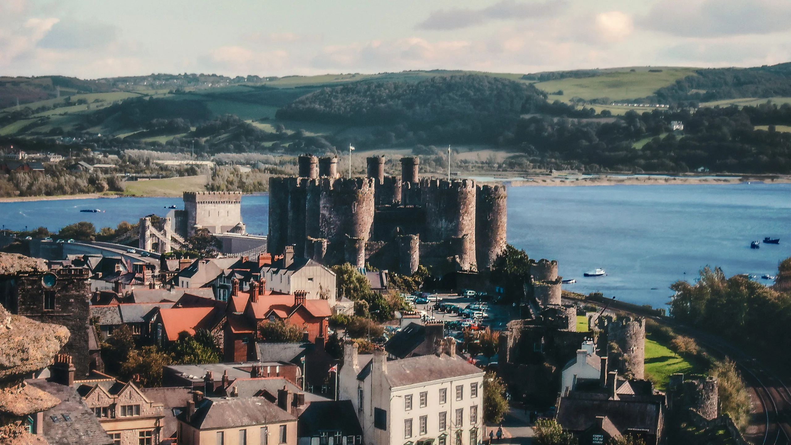 Conwy Castle standing tall among the buildings of the town with the sea in the background