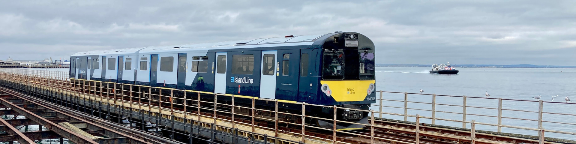 Train travelling across low-level viaduct with sea and hover boat in the background