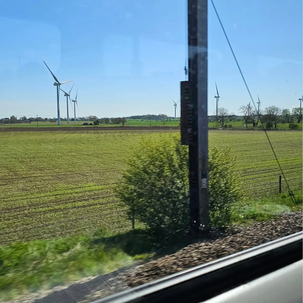 View from the train of green farmland with six wind turbines stretching into the distance #scenicrailview
