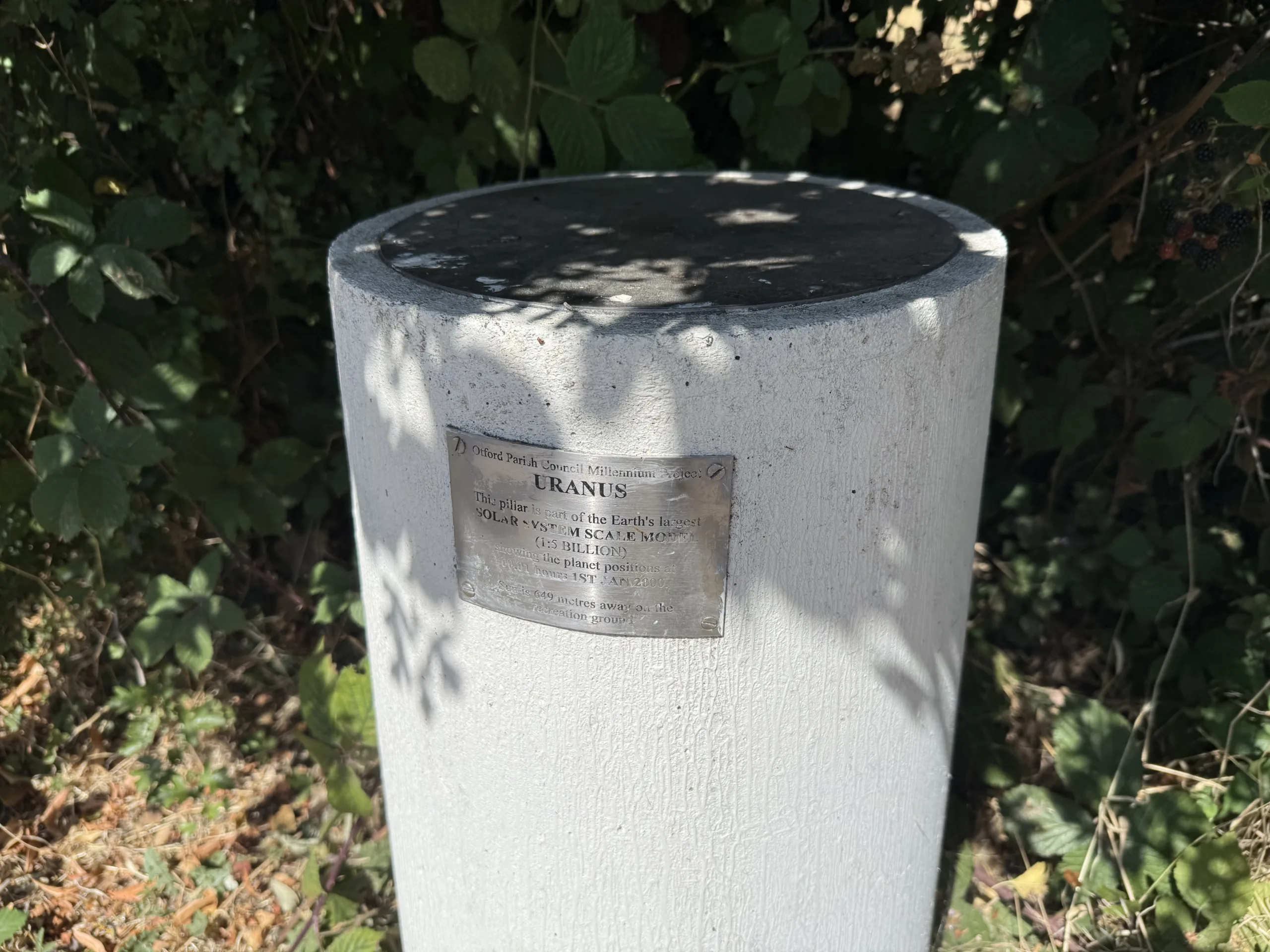A white post in the ground as part of the Otford Solar System Walk.